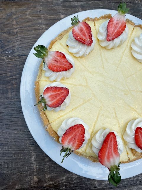 A baked vanilla cheesecake with fresh strawberries on whipped cream